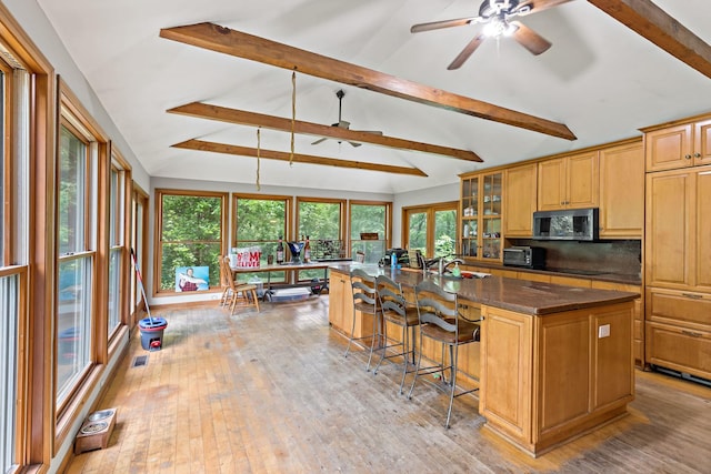 3457 W Hamilton Rd, Monee, IL 60449 - kitchen with stainless steel microwave, a ceiling fan, a breakfast bar, a kitchen island with sink, and black electric stovetop