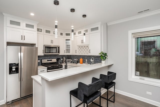 4634 S Langley Ave, Chicago, IL 60653 - kitchen with stainless steel appliances, a kitchen breakfast bar, light countertops, dark wood-style flooring, and crown molding