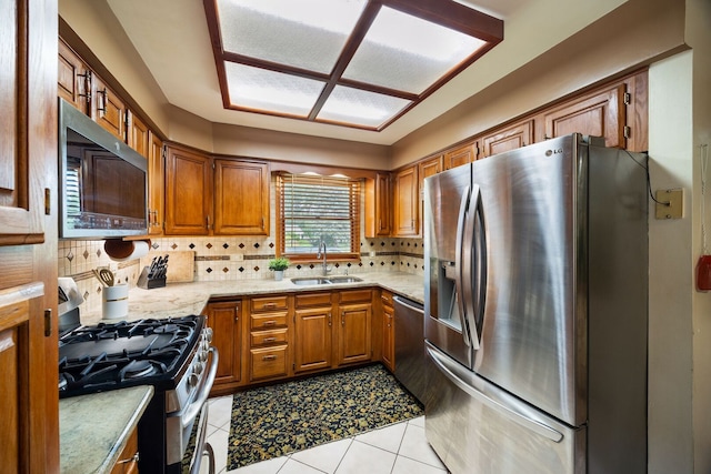 267 N Idlewild Ave, Mundelein, IL 60060 - kitchen featuring appliances with stainless steel finishes, brown cabinetry, backsplash, light tile patterned floors, and light stone countertops