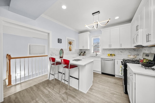 3039 S Kolin Ave, Chicago, IL 60623 - kitchen with stainless steel appliances, a peninsula, white cabinetry, light countertops, and ornamental molding