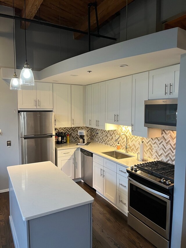 2210 W Wabansia Ave Unit 302, Chicago, IL 60647 - kitchen featuring appliances with stainless steel finishes, dark wood-style floors, tasteful backsplash, a center island, and a towering ceiling