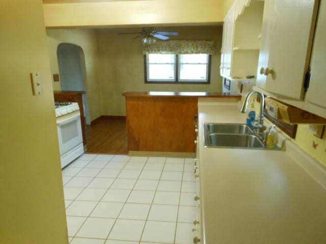 15409 S Union Pl, Plainfield, IL 60544 - kitchen featuring white gas range, ceiling fan, arched walkways, light countertops, and a peninsula