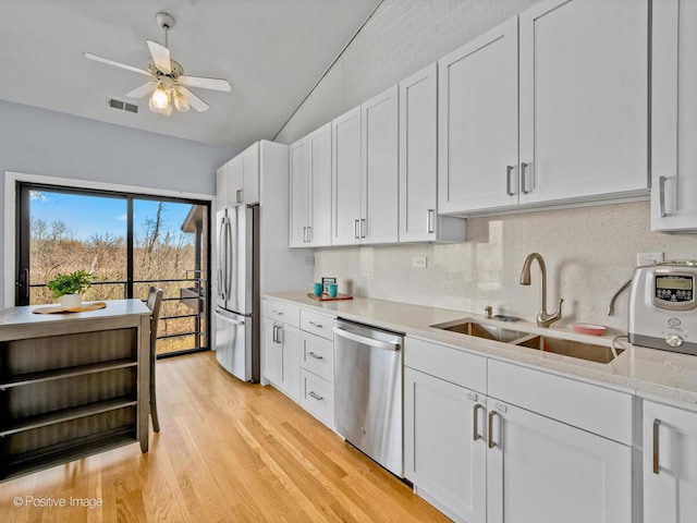 1039 Deerfield Pl Unit 1039, Highland Park, IL 60035 - kitchen featuring appliances with stainless steel finishes, a ceiling fan, white cabinetry, light wood finished floors, and backsplash