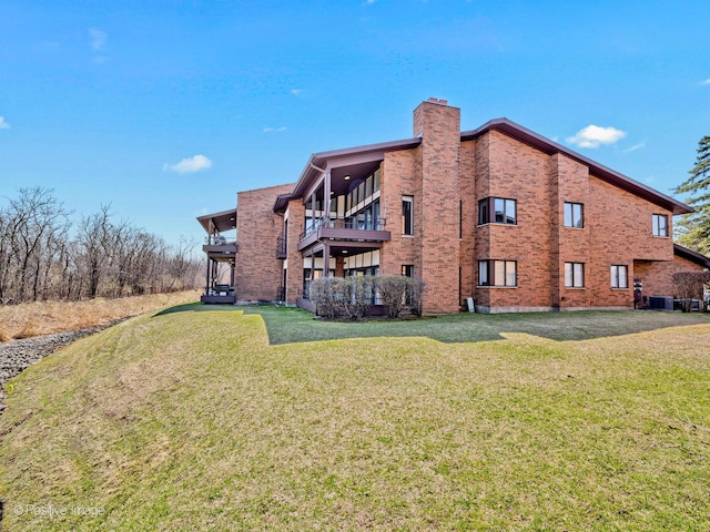 1039 Deerfield Pl Unit 1039, Highland Park, IL 60035 - rear view of house featuring a chimney, a balcony, brick siding, and a lawn
