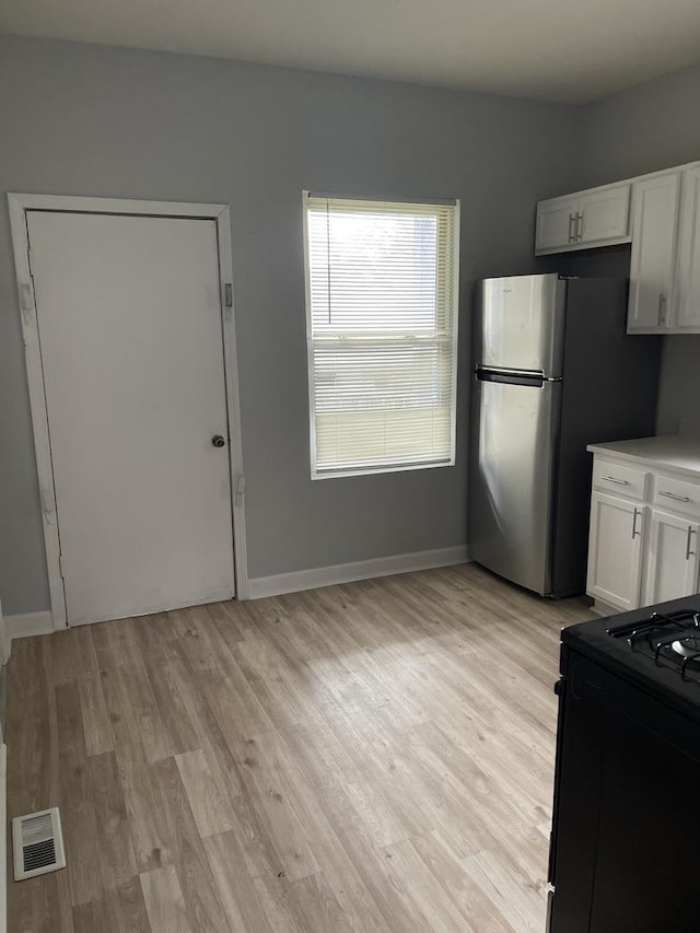 7535 S Vernon Ave, Chicago, IL 60619 - kitchen featuring black range oven, white cabinetry, light wood finished floors, freestanding refrigerator, and light countertops