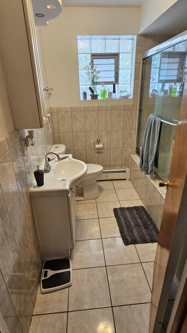 3201 Armitage Ave, Melrose Park, IL 60160 - full bath featuring tile patterned flooring, vanity, a baseboard radiator, tile walls, and tiled shower / bath combo