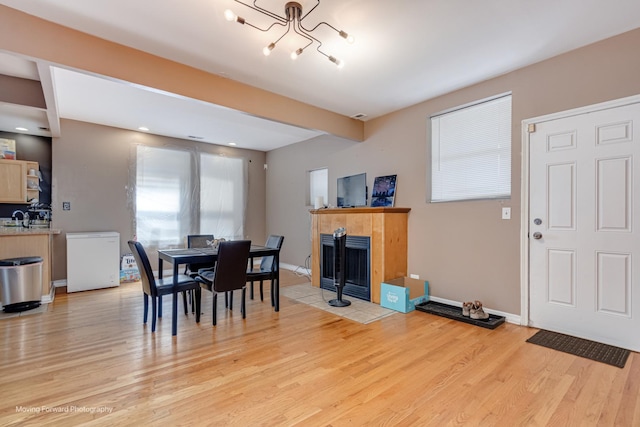 1423 E 68th St Unit 2, Chicago, IL 60637 - dining space with light wood-style flooring, a chandelier, and a tiled fireplace