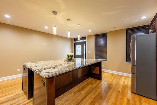 2012 W Coulter St, Chicago, IL 60608 - kitchen with freestanding refrigerator, a center island, light wood finished floors, decorative light fixtures, and light stone countertops