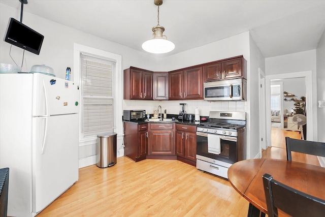 1637 N Keeler Ave, Chicago, IL 60639 - kitchen featuring appliances with stainless steel finishes, dark countertops, light wood finished floors, hanging light fixtures, and backsplash