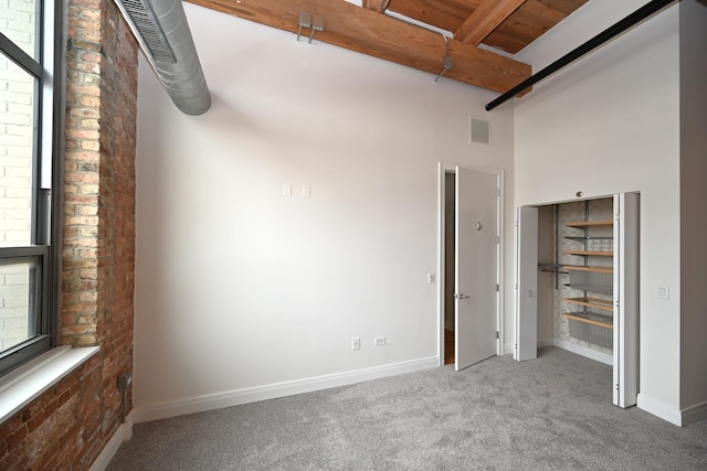 770 W Gladys Ave Unit 606, Chicago, IL 60661 - unfurnished bedroom featuring carpet floors, a towering ceiling, beamed ceiling, and brick wall