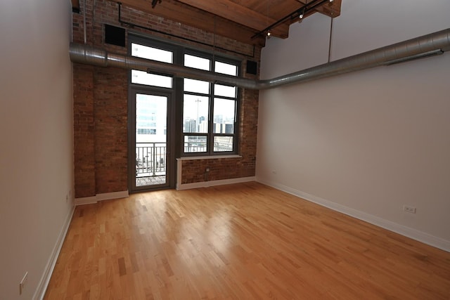 770 W Gladys Ave Unit 606, Chicago, IL 60661 - spare room featuring a high ceiling, brick wall, wood finished floors, and rail lighting