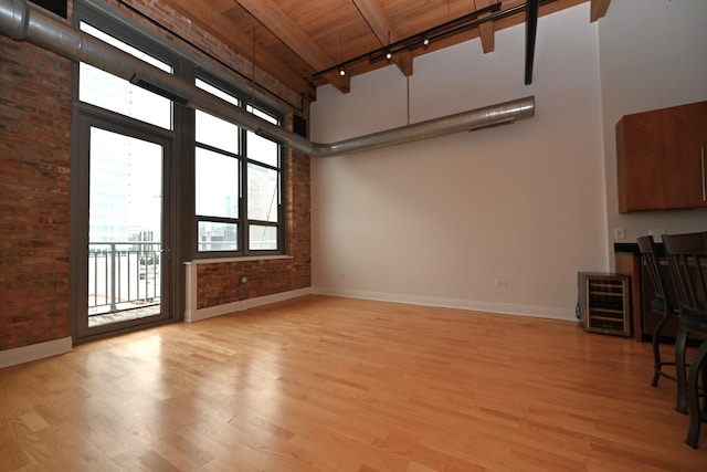 770 W Gladys Ave Unit 606, Chicago, IL 60661 - unfurnished living room featuring a towering ceiling, a wooden ceiling with exposed beams, light wood finished floors, brick wall, and wine cooler