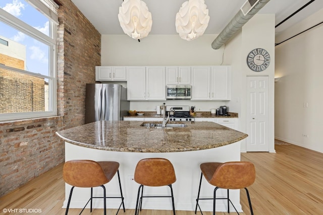 1907 N Milwaukee Ave Unit 307, Chicago, IL 60647 - kitchen with brick wall, appliances with stainless steel finishes, a towering ceiling, light wood-type flooring, and white cabinetry