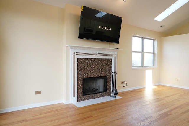 2665 W Warren Blvd Unit 3, Chicago, IL 60612 - unfurnished living room featuring a tiled fireplace, wood finished floors, a skylight, and vaulted ceiling