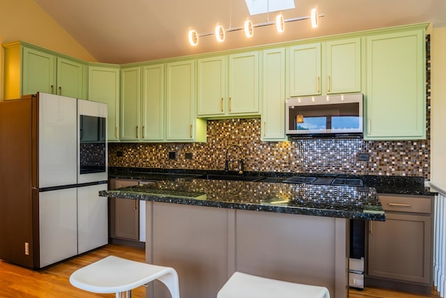 2665 W Warren Blvd Unit 3, Chicago, IL 60612 - kitchen featuring green cabinetry, freestanding refrigerator, lofted ceiling, stainless steel microwave, and backsplash