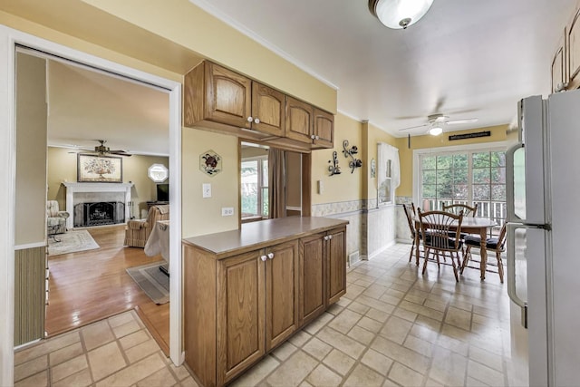859 S Mount Prospect Rd, Des Plaines, IL 60016 - kitchen with a ceiling fan, freestanding refrigerator, a fireplace, light stone finish floors, and brown cabinets