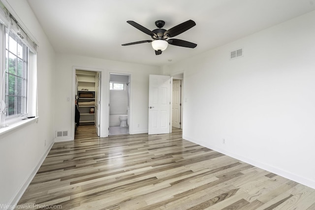 2004 Pine Dr, Mchenry, IL 60051 - unfurnished bedroom featuring a walk in closet, light wood finished floors, multiple windows, and ensuite bath