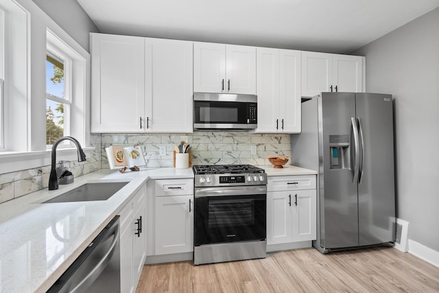 526 S Calumet Ave, Aurora, IL 60506 - kitchen featuring stainless steel appliances, white cabinets, backsplash, light stone countertops, and light wood-style floors