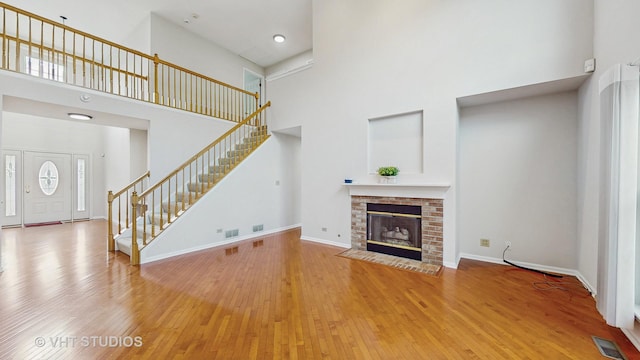 1291 White Chapel Ln, Algonquin, IL 60102 - unfurnished living room with a towering ceiling, stairway, hardwood / wood-style floors, and a brick fireplace