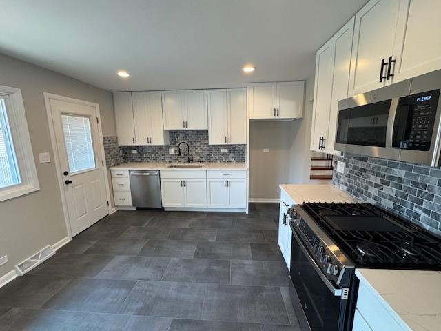 535 Florian Dr, Des Plaines, IL 60016 - kitchen featuring appliances with stainless steel finishes, white cabinetry, backsplash, and recessed lighting