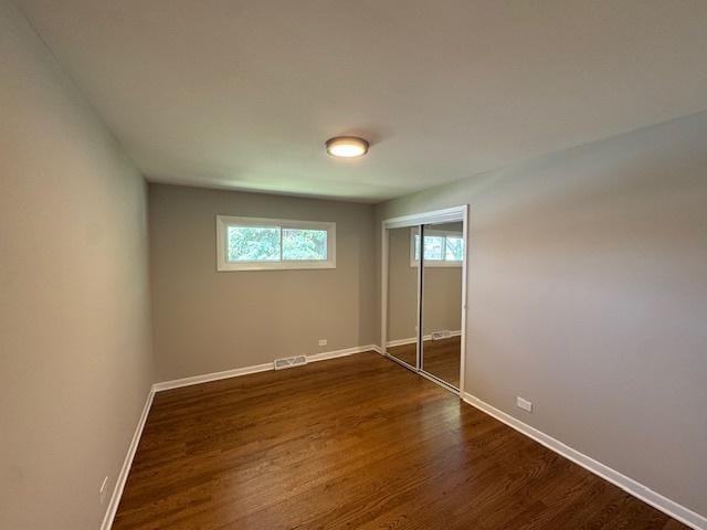 535 Florian Dr, Des Plaines, IL 60016 - unfurnished bedroom featuring multiple windows, dark wood finished floors, and a closet