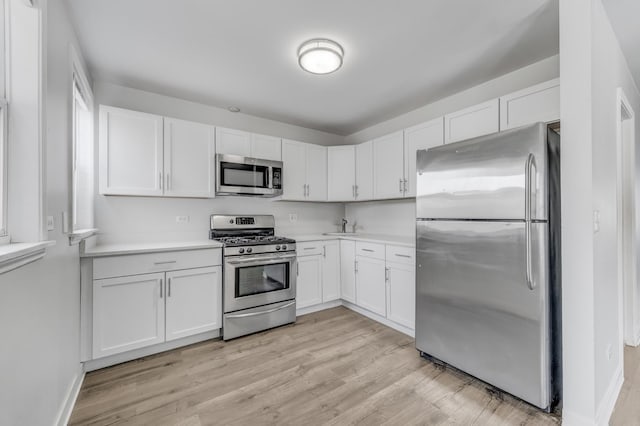 1166 W Cullerton St, Chicago, IL 60608 - kitchen with stainless steel appliances, white cabinetry, light countertops, and light wood-style floors