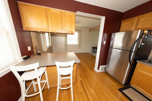1406 Portsmouth Ave, Westchester, IL 60154 - kitchen featuring freestanding refrigerator, light wood-style flooring, a kitchen breakfast bar, a peninsula, and light countertops