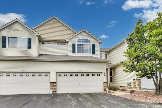 574 S Jade Ln, Round Lake, IL 60073 - traditional-style house featuring an attached garage, stone siding, and asphalt driveway