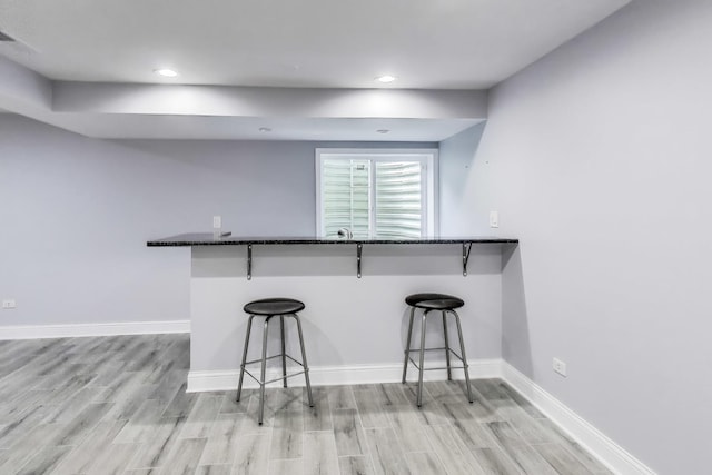 574 S Jade Ln, Round Lake, IL 60073 - kitchen with light wood-style flooring, a kitchen breakfast bar, dark stone counters, recessed lighting, and a peninsula