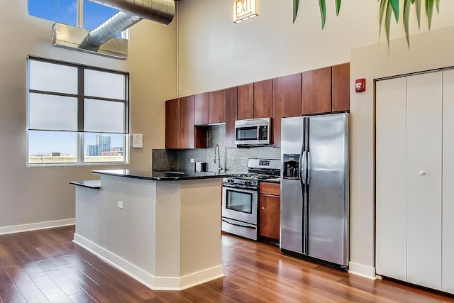 901 W Madison St Unit 609, Chicago, IL 60607 - kitchen with a towering ceiling, appliances with stainless steel finishes, dark wood-style floors, dark countertops, and decorative backsplash