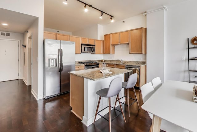 901 W Madison St Unit 609, Chicago, IL 60607 - kitchen with appliances with stainless steel finishes, rail lighting, a center island, light stone counters, and a breakfast bar area