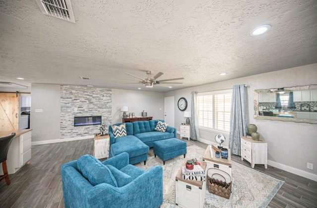 living room featuring a textured ceiling, a barn door, visible vents, and wood tiled floor