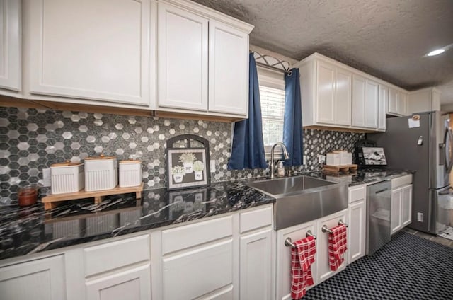 kitchen featuring dark stone counters, a sink, white cabinetry, backsplash, and dishwasher