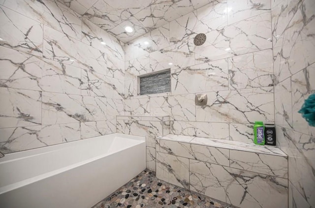 bathroom featuring stone wall, a bathtub, and tile walls