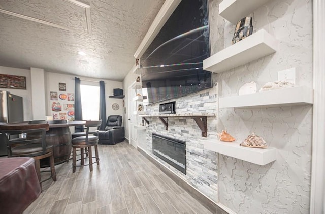 kitchen featuring a fireplace, a kitchen breakfast bar, a textured ceiling, and wood finish floors