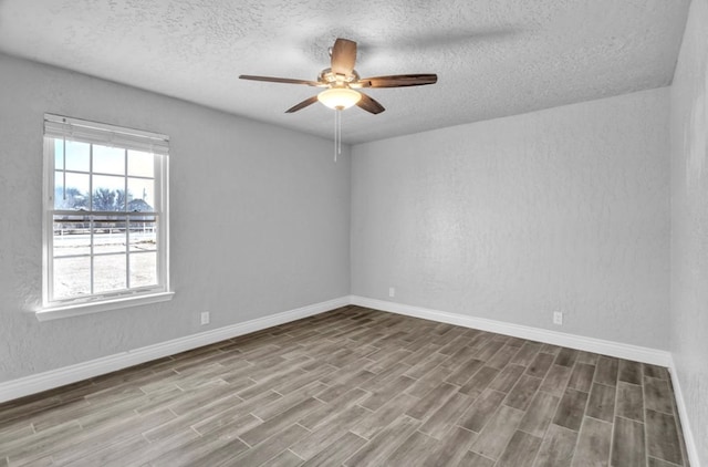 empty room with ceiling fan, a textured ceiling, light wood-style flooring, and baseboards