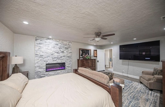 bedroom with recessed lighting, ceiling fan, a stone fireplace, a textured ceiling, and wood finished floors