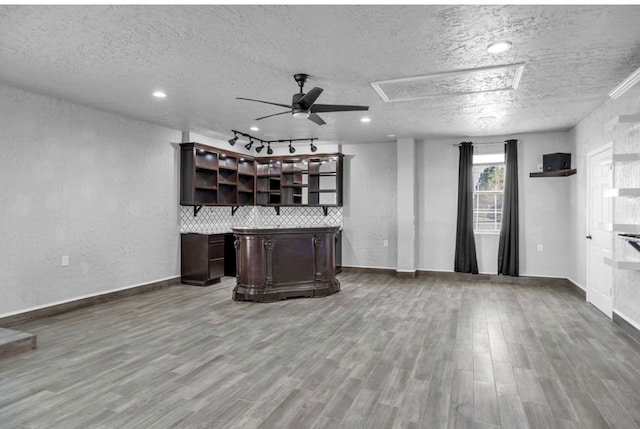 bar with ceiling fan, a textured ceiling, baseboards, and wood finished floors