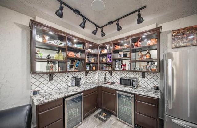 bar featuring stainless steel appliances, wine cooler, wet bar, and tasteful backsplash