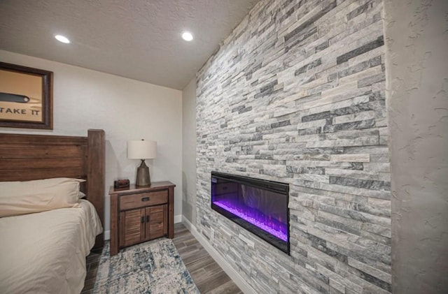 bedroom featuring wood finish floors, a fireplace, baseboards, and recessed lighting