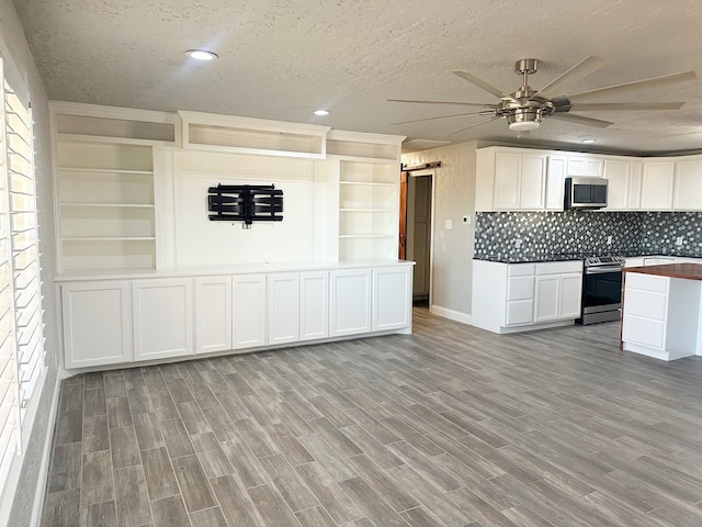 kitchen with ceiling fan, a textured ceiling, a barn door, light wood-style flooring, and appliances with stainless steel finishes