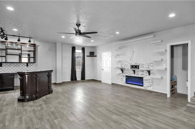 kitchen with a textured ceiling, a fireplace, wood finished floors, a ceiling fan, and decorative backsplash