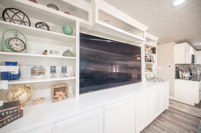 kitchen with white cabinetry, light countertops, a textured ceiling, and wood finished floors