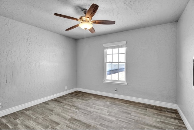 unfurnished room with ceiling fan, a textured wall, light wood finished floors, and baseboards