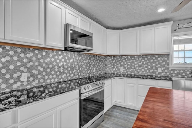 kitchen featuring white cabinetry, appliances with stainless steel finishes, decorative backsplash, and a textured ceiling