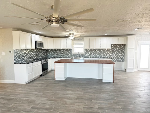 kitchen featuring stainless steel appliances, tasteful backsplash, wood tiled floor, white cabinetry, and a sink