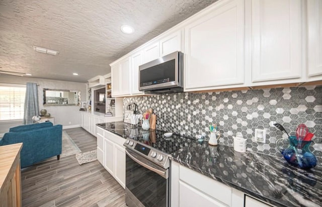 kitchen with white cabinetry, stainless steel appliances, wooden counters, and open floor plan