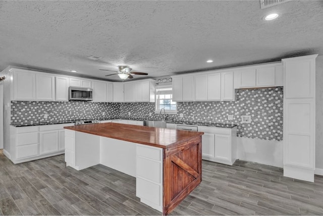 kitchen featuring stainless steel microwave, a sink, and white cabinetry