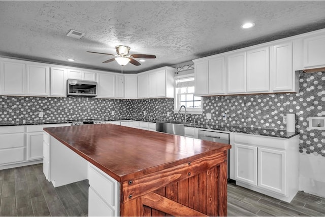 kitchen with dark countertops, white cabinets, stainless steel appliances, and a sink