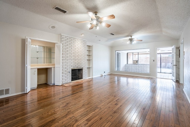 unfurnished living room featuring built in features, a brick fireplace, visible vents, and wood finished floors